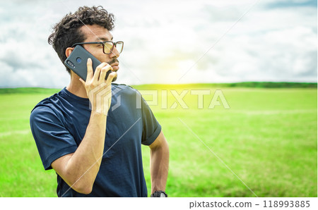 Man calling by cell phone, young man in the field calling by cell phone 118993885