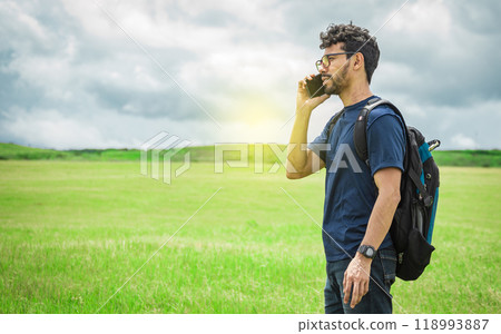 Man calling by cell phone, young man in the field calling by cell phone 118993887