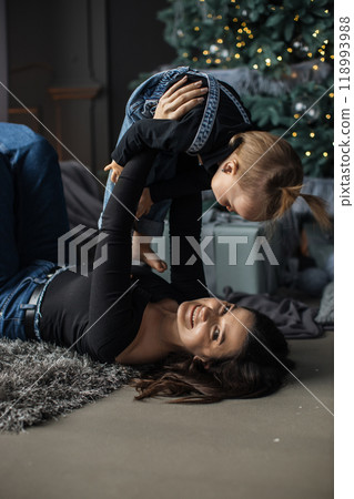 Mother and daughter playing near Christmas tree indoors Mother and daughter playing near Christmas tree indoors 118993988