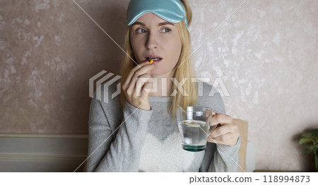 A woman cannot fall asleep and wants to drink a capsule with melatonin, a sleeping pill. Manifestations of jitlag or insomnia. Regulation of biological rhythms A woman cannot fall asleep and wants to drink a capsule with melatonin, a sleeping pill. Manifestations of jitlag or insomnia. Regulation of biological rhythms 118994873