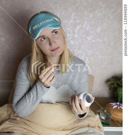 A woman cannot fall asleep and wants to drink a capsule with melatonin, a sleeping pill. Manifestations of jitlag or insomnia. Regulation of biological rhythms A woman cannot fall asleep and wants to drink a capsule with melatonin, a sleeping pill. Manifestations of jitlag or insomnia. Regulation of biological rhythms 118994889