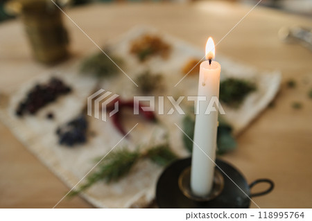 Candle on an old metal stand. Preparing nutritional supplements to improve human immunity and health. Dried herbs and seasonings.  118995764