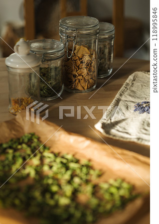 Dried flowers and herbs stored in sealed glass jars on a wooden table. Prepared for winter use Dried flowers and herbs stored in sealed glass jars on a wooden table. Prepared for winter use 118995846