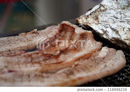 Close-up of pork belly being grilled on a charcoal grill. Close-up of pork belly being grilled on a charcoal grill. 118998238
