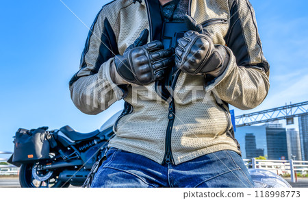 Male rider preparing motorcycle chest protector 118998773