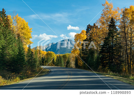 Scenic country mountain road in autumn color forest against blue sky. Bow Valley Parkway ( Highway 1A ), Banff National Park, Alberta, Canada. Canadian Rockies beautiful natural scenery. 118998893