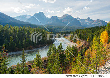 Banff National Park Bow river autumn landscape. Alberta, Canada. Majestic mountains, forests in yellow and green color against blue sky. Canadian Rockies beautiful natural scenery. Banff National Park Bow river autumn landscape. Alberta, Canada. Majestic mountains, forests in yellow and green color against blue sky. Canadian Rockies beautiful natural scenery. 118998895