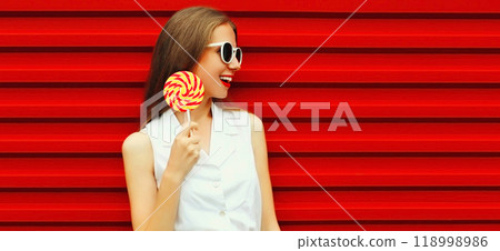 Summer portrait of happy smiling young woman with lollipop on red background Summer portrait of happy smiling young woman with lollipop on red background 118998986