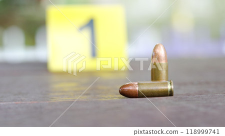 9 mm pistol bullet lying on dark wooden bench with blur number 1 sign on blur background. Concepts of criminal investigations and shooting sport. 118999741