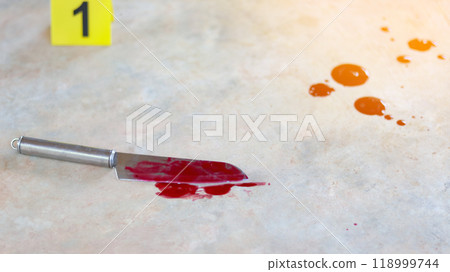 A bloodstained stainless steel knife lying on a concrete floor, with a blurred yellow number 1 sign nearby and blood splatter surrounding the scene, evoking a sense of crime investigation. 118999744
