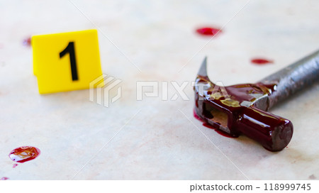 A bloodstained steel hammer lying on a concrete floor, with a blurred yellow marker number 1 and scattered blood drops, symbolizing a violent crime scene under investigation. A bloodstained steel hammer lying on a concrete floor, with a blurred yellow marker number 1 and scattered blood drops, symbolizing a violent crime scene under investigation. 118999745