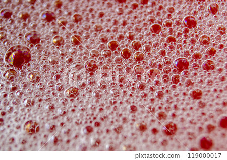 Macro shot of bubbles forming on a water surface with red background 119000017