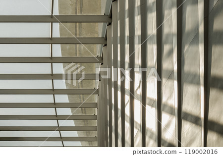 View of Sunlight shining through glass roof and creating shadows on a wall. View of Sunlight shining through glass roof and creating shadows on a wall. 119002016