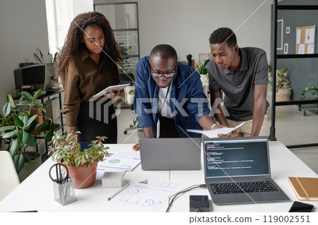 African American team of young and successful developers discussing and creating new codes in white office 119002551