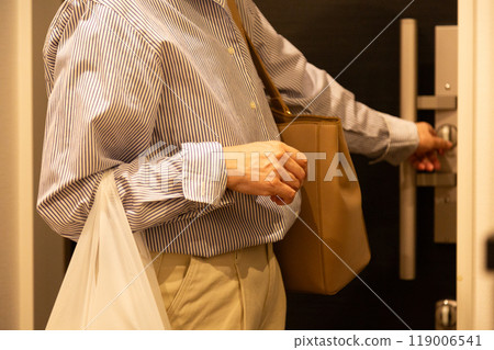 A senior woman who returns home to her apartment and locks the front door 119006541