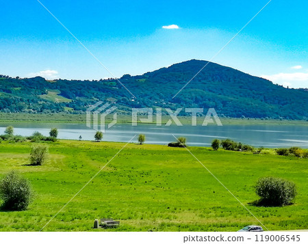 Green natural meadow with grass and beautiful sky. landscape with mountain range covered with green forest and clouds. High quality photo Green natural meadow with grass and beautiful sky. landscape with mountain range covered with green forest and clouds. High quality photo 119006545