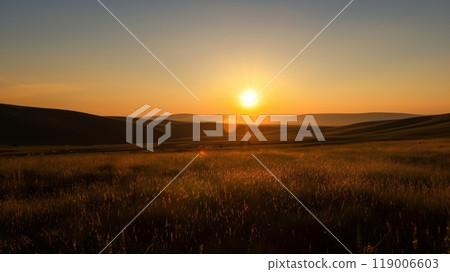 A prairie silhouette stretches to distant hills bathed in the warm hues of a setting sun, casting golden light. 119006603