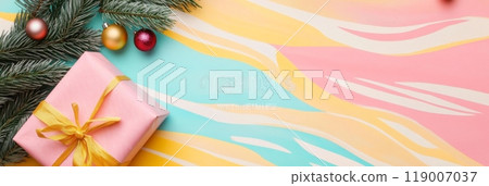 A beautifully wrapped pink Christmas gift with a yellow ribbon beside festive ornaments and pine branches A beautifully wrapped pink Christmas gift with a yellow ribbon beside festive ornaments and pine branches 119007037