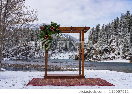 An artistic wooden pavilion decoration and Bow Falls in the background in winter. A concept of marriage. Banff National Park, Bow River. 119007911