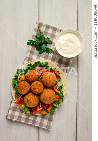 Tortillas, wrapped falafel balls, with fresh vegetables, vegetarian healthy food, on a wooden white background, no people, selective focus. Tortillas, wrapped falafel balls, with fresh vegetables, vegetarian healthy food, on a wooden white background, no people, selective focus. 119008044