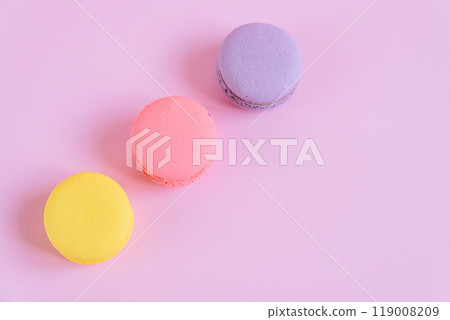 Tasty violet, pink and yellow french macaron cakes on pink background. Tasty violet, pink and yellow french macaron cakes on pink background. 119008209