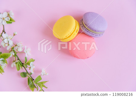 Delicious violet and yellow macarons and blooming branch on pink background. 119008216