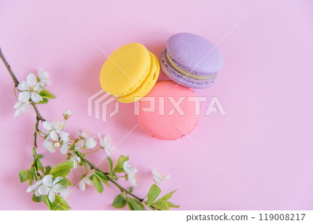 Delicious violet and yellow macarons and blooming branch on pink background. 119008217