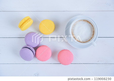 Sweet delicious colorful macarons and cup of coffee on white wooden background. Sweet delicious colorful macarons and cup of coffee on white wooden background. 119008230