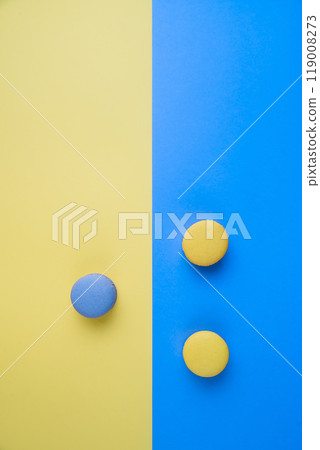 Sweet tasty blue and yellow french macaron cakes on yellow and blue background. Sweet tasty blue and yellow french macaron cakes on yellow and blue background. 119008273