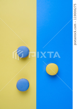 Sweet tasty blue and yellow french macaron cakes on yellow and blue background. Sweet tasty blue and yellow french macaron cakes on yellow and blue background. 119008275