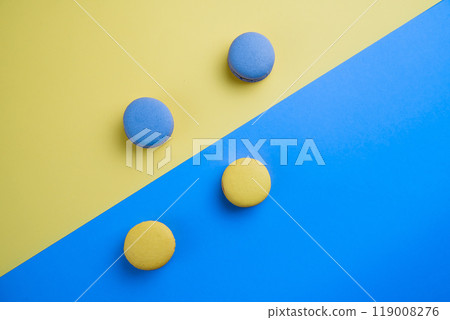 Sweet tasty blue and yellow french macaron cakes on yellow and blue background. Sweet tasty blue and yellow french macaron cakes on yellow and blue background. 119008276