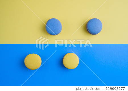 Sweet tasty blue and yellow french macaron cakes on yellow and blue background. Sweet tasty blue and yellow french macaron cakes on yellow and blue background. 119008277