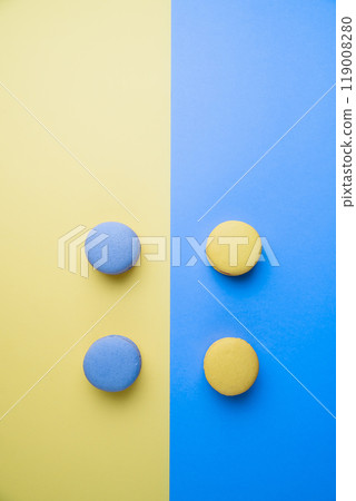 Sweet tasty blue and yellow french macaron cakes on yellow and blue background. 119008280