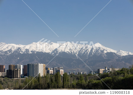 City at foot of mountains with snow-capped peaks. multi-storey residential buildings against backdrop of mountain range 119008318