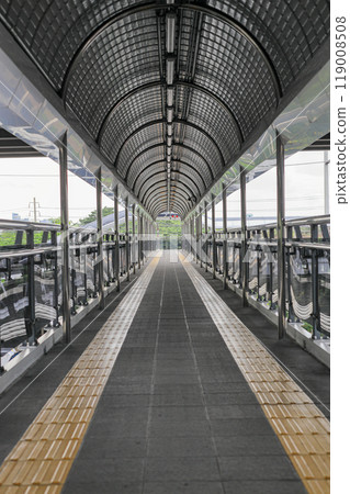 Pedestrian pathway or corridor or hallway between train station and other building. Pedestrian pathway or corridor or hallway between train station and other building. 119008508
