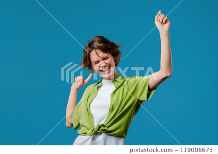 Funny pretty 30s aged woman having fun, favorite music, smiling, dancing on blue studio background. Music, dance concept 119008673