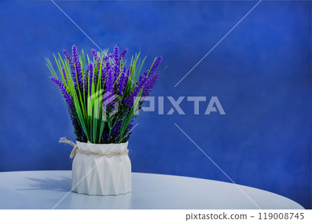 Bouquet of lavender in a white vase on a blue background. Decorating a room with flowers. Bouquet of lavender in a white vase on a blue background. Decorating a room with flowers. 119008745