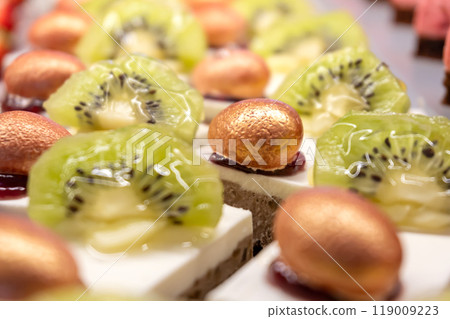 Cakes decorated with kiwi slices and nuts in sugar glaze. Sweet dessert. Close-up. Cakes decorated with kiwi slices and nuts in sugar glaze. Sweet dessert. Close-up. 119009223