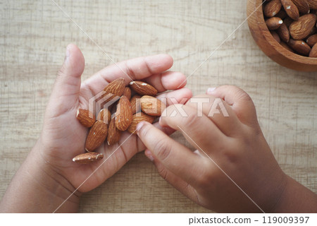top view of child hand pick almond nuts top view of child hand pick almond nuts 119009397