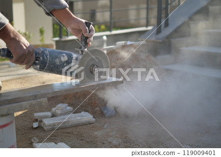 Concrete cutting is currently being conducted with a power tool on a busy construction site Concrete cutting is currently being conducted with a power tool on a busy construction site 119009401