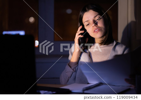 Girl is working on a laptop at night at home. Girl is working on a laptop at night at home. 119009434