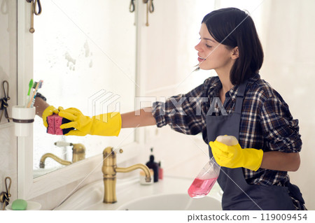Young woman is washing mirror in the bathrom. Young woman is washing mirror in the bathrom. 119009454