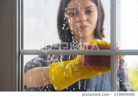 Woman washes the windows with a detergent. Woman washes the windows with a detergent. 119009480