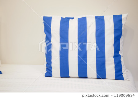A blue and white striped pillow placed nicely on a cozy bed, adding a touch of style 119009654