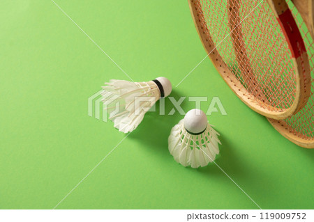 Two wooden badminton rackets and white feather badminton shuttlecocks on green background. View from above. Concept racket sport. Leisure games. Two wooden badminton rackets and white feather badminton shuttlecocks on green background. View from above. Concept racket sport. Leisure games. 119009752