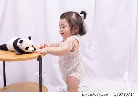 [Baby with twin tails standing up holding onto a table] 119010714