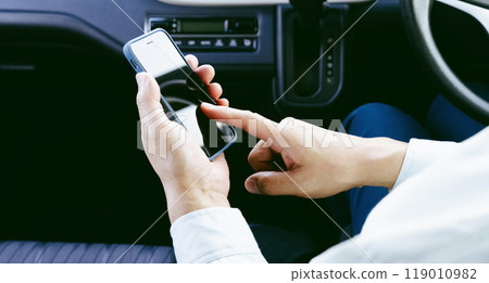 A man in work clothes operating a smartphone in a car A man in work clothes operating a smartphone in a car 119010982