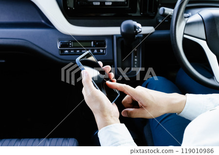A man in work clothes operating a smartphone in a car 119010986