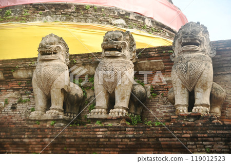 Beautiful and complete lion statue at the base of the main pagoda of Wat Mae Nang Pluem. which is another ancient temple in Phra Nakhon Si Ayutthaya Historical Park in Thailand. Beautiful and complete lion statue at the base of the main pagoda of Wat Mae Nang Pluem. which is another ancient temple in Phra Nakhon Si Ayutthaya Historical Park in Thailand. 119012523