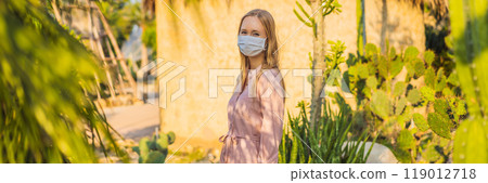 BANNER, LONG FORMAT beautiful stylish young woman in pink dress in desert among the cacti, wearing a medical mask during COVID-19 coronavirus, traveling in Africa on safari, exploring nature, sunny BANNER, LONG FORMAT beautiful stylish young woman in pink dress in desert among the cacti, wearing a medical mask during COVID-19 coronavirus, traveling in Africa on safari, exploring nature, sunny 119012718